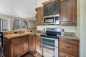 Kitchen featuring dark wood-type flooring, stainless steel appliances, and kitchen peninsula