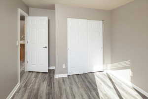 Unfurnished bedroom with wood-type flooring and a closet