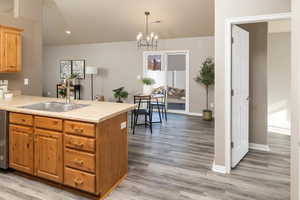 Kitchen with sink, hardwood / wood-style flooring, hanging light fixtures, and kitchen peninsula