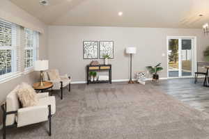 Sitting room featuring lofted ceiling, dark carpet, and an inviting chandelier