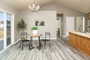 Dining room featuring lofted ceiling, sink, a notable chandelier, and light hardwood / wood-style floors