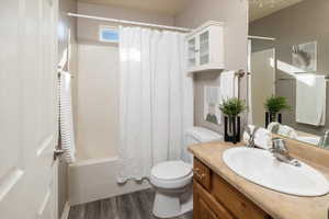 Full bathroom with vanity, wood-type flooring, toilet, and shower / tub combo with curtain