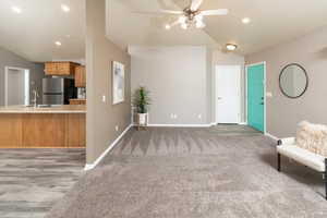 Unfurnished living room featuring dark carpet, ceiling fan, sink, and vaulted ceiling