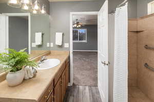 Bathroom with a shower with curtain, ceiling fan, vanity, and wood-type flooring