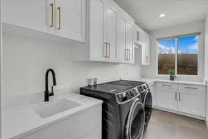 Washroom featuring independent washer and dryer, sink, cabinets, and light tile patterned flooring