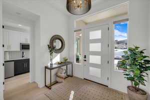 Foyer entrance featuring sink, a chandelier, and light wood-type flooring