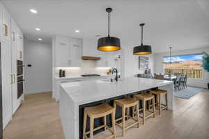 Kitchen with white cabinetry, gas stovetop, decorative light fixtures, and a spacious island