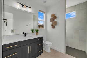 Bathroom featuring vanity, a tile shower, tile patterned floors, and toilet