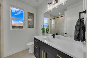 Bathroom featuring tile patterned flooring, toilet, plenty of natural light, and a shower with shower door