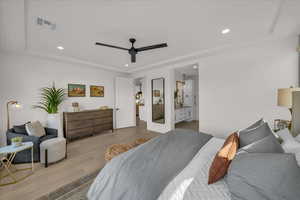 Bedroom featuring a raised ceiling, ceiling fan, and light wood-type flooring