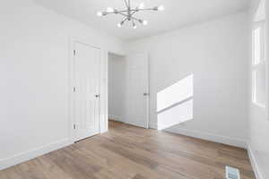 Spare room featuring light hardwood / wood-style flooring and a notable chandelier