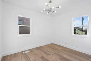 Spare room with wood-type flooring and a chandelier