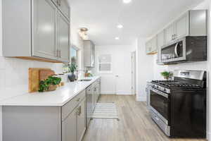 Kitchen featuring tasteful backsplash, sink, gray cabinets, and stainless steel appliances