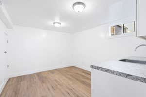 Unfurnished room featuring sink, light hardwood / wood-style flooring, and a textured ceiling