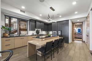 Kitchen featuring sink, light hardwood / wood-style floors, a kitchen island, decorative light fixtures, and light brown cabinets