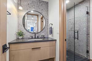 Bathroom with a shower with door, vanity, and decorative backsplash