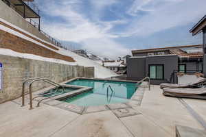 View of swimming pool featuring a community hot tub, a mountain view, and a patio area