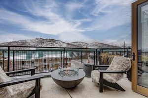 Snow covered back of property with a mountain view and an outdoor fire pit