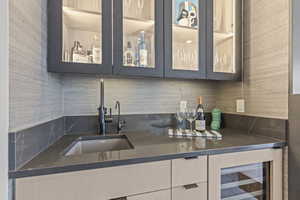 Kitchen with sink, decorative backsplash, and beverage cooler