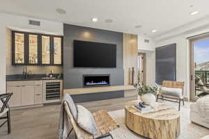 Living room with wine cooler, a fireplace, wet bar, and light hardwood / wood-style flooring