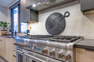 Kitchen with tasteful backsplash, double oven range, sink, and wall chimney exhaust hood