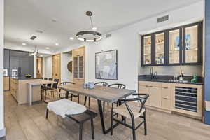 Dining room featuring wine cooler, wet bar, and light hardwood / wood-style floors