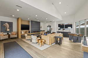 Living room with elevator, high vaulted ceiling, and light hardwood / wood-style floors