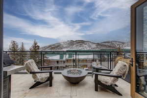 Snow covered back of property with a mountain view and a fire pit