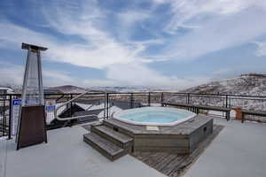 Snow covered pool with a mountain view and a hot tub