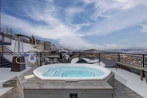 Snow covered pool featuring a mountain view and a hot tub