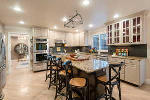 Kitchen with stainless steel appliances, a kitchen island, white cabinets, and light stone counters