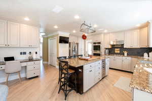 Kitchen featuring white cabinetry, light wood-type flooring, a center island, and appliances with stainless steel finishes