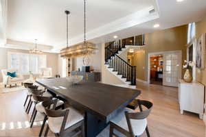 Dining room with french doors, light hardwood / wood-style flooring, and a tray ceiling