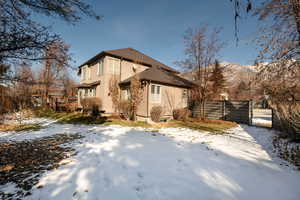 Snow covered back of property featuring a deck with mountain view