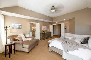 Carpeted bedroom with ensuite bath, vaulted ceiling, and ceiling fan