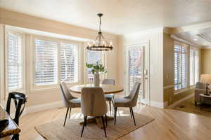 Dining area with an inviting chandelier, ornamental molding, and light hardwood / wood-style floors