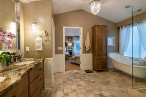 Bathroom with lofted ceiling, vanity, and a bathtub