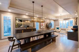 Dining area featuring a tray ceiling, a chandelier, and light hardwood / wood-style floors