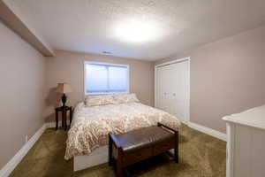 Carpeted bedroom featuring a closet and a textured ceiling