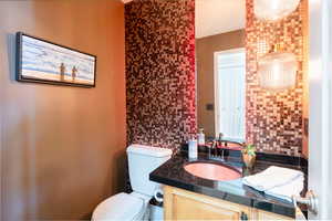 Bathroom with vanity, tasteful backsplash, and toilet