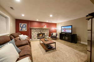 Living room featuring a stone fireplace and carpet floors