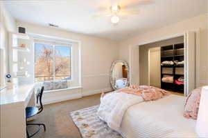 Carpeted bedroom featuring ceiling fan and a closet