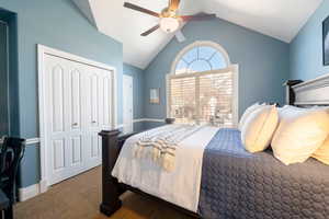 Carpeted bedroom featuring ceiling fan and vaulted ceiling