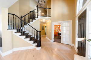 Entrance foyer with crown molding, wood-type flooring, and a high ceiling