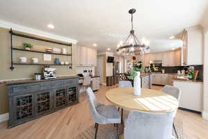 Dining area featuring an inviting chandelier, ornamental molding, sink, and light wood-type flooring