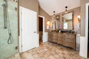 Bathroom with lofted ceiling, vanity, a shower with shower door, and toilet