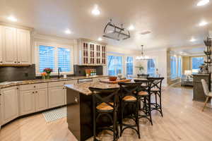 Kitchen with sink, a kitchen bar, a kitchen island, stone countertops, and decorative light fixtures