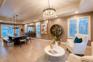 Living room featuring plenty of natural light, a tray ceiling, a chandelier, and light hardwood / wood-style flooring