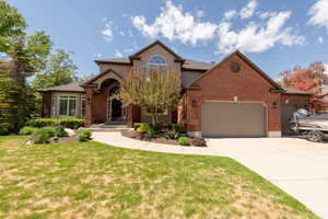 View of front of property featuring a garage, a front lawn, driveway, and brick siding