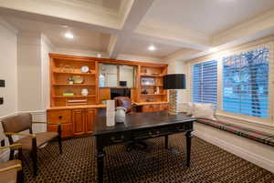 Office space with built in desk, beamed ceiling, carpet floors, coffered ceiling, and crown molding